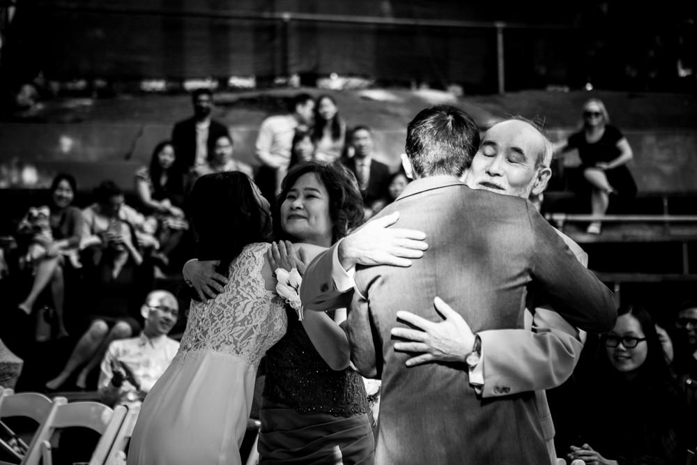 Black and white candid shot of groom hugging father at Piedmont Community Hall wedding