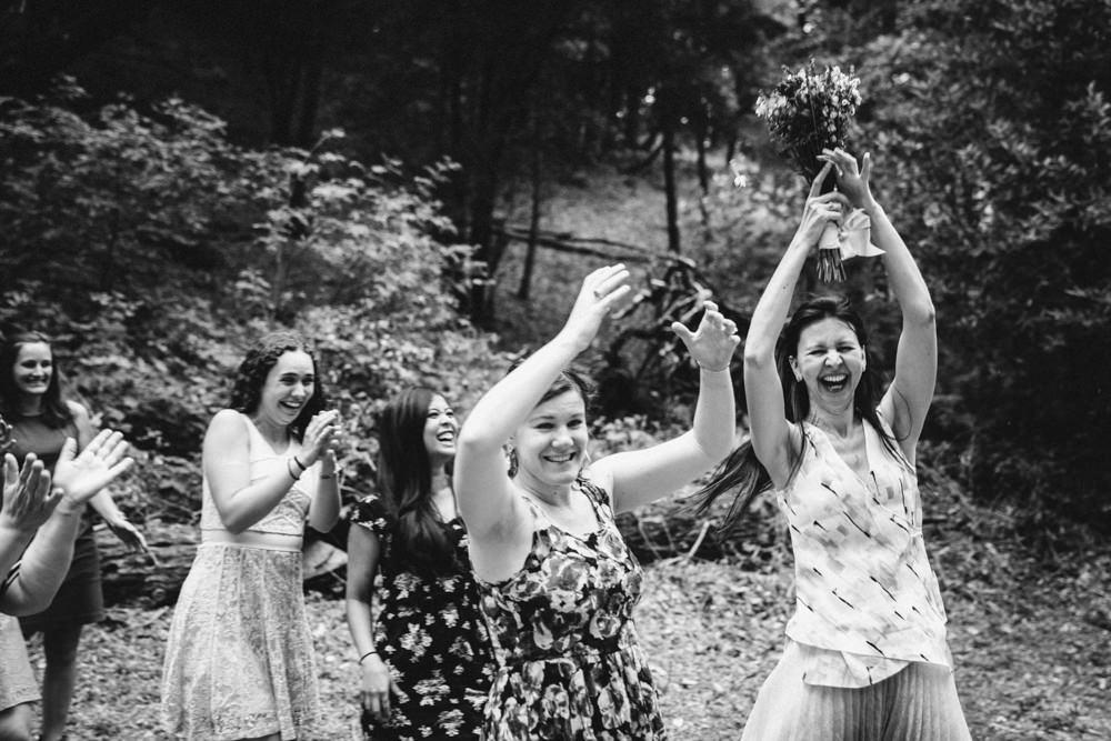 Woman catches bouquet during outdoor wedding
