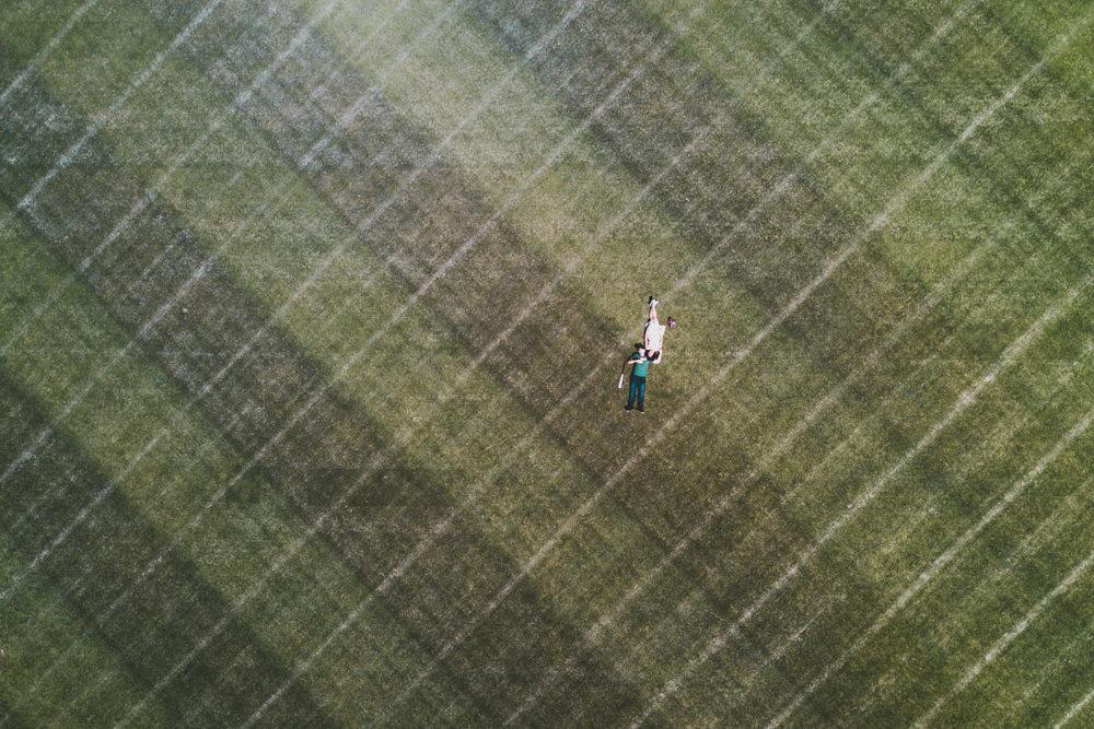 Drone shot of couple on Oakland Coliseum Ricky Henderson field