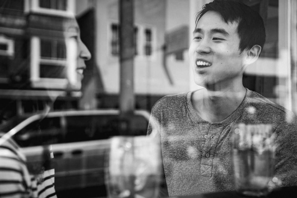 Couple through window reflection at coffee shop during engagement shoot