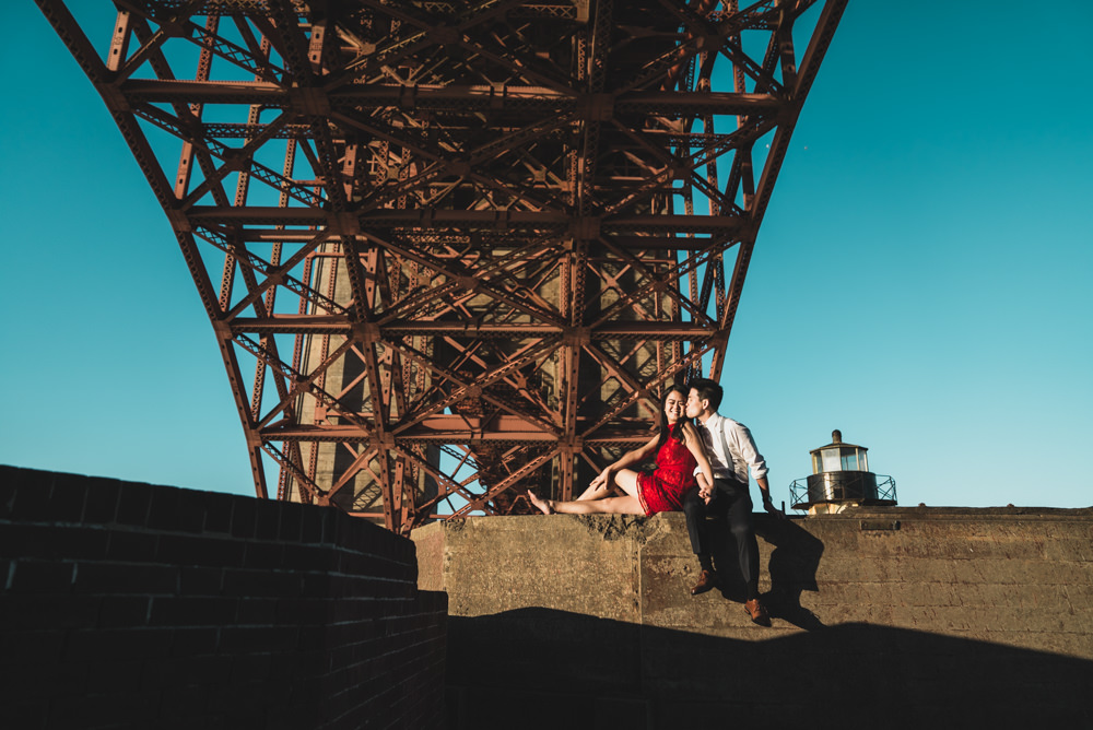 Couple sitting under golden gate bridge