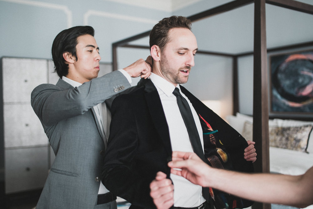 Candid wedding photo of groom showing off velvet suit jacket