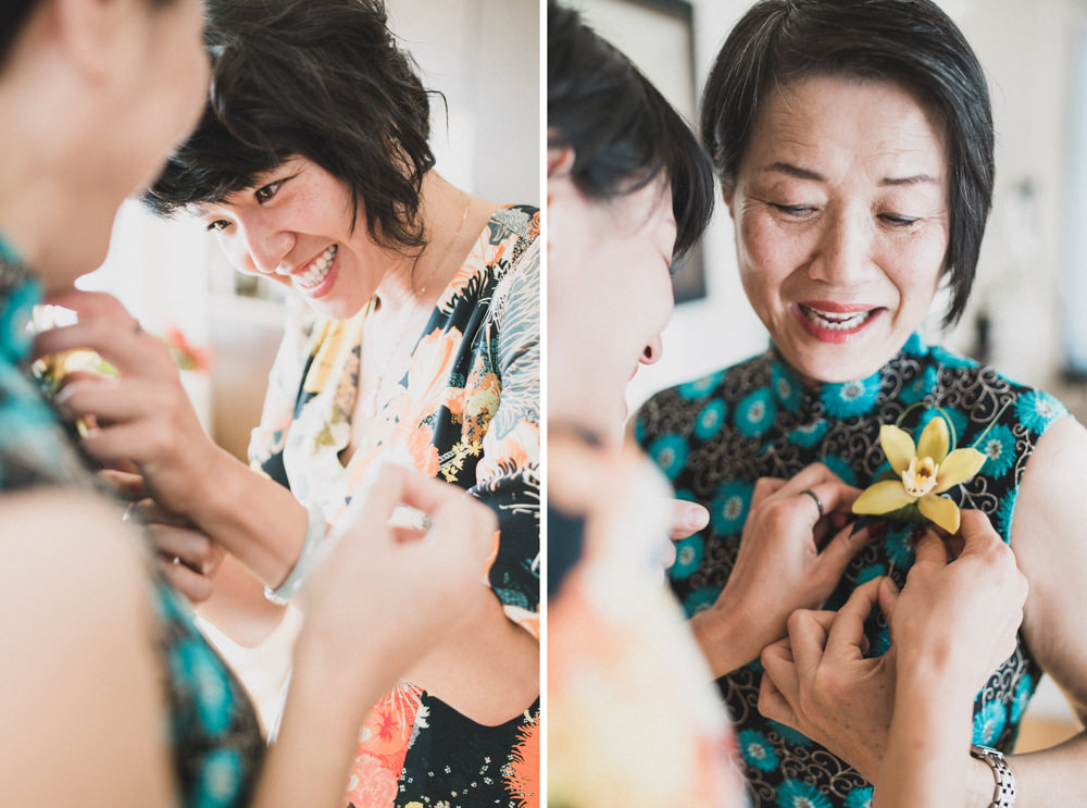 Bride in floral dress putting boutonniere on mother before wedding