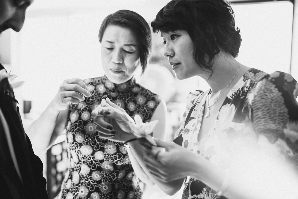 Black and white shot of bride putting on boutonniere