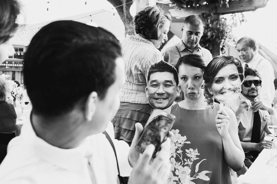 Candid shot of guest making funny face with bride and groom cut-out at wedding reception