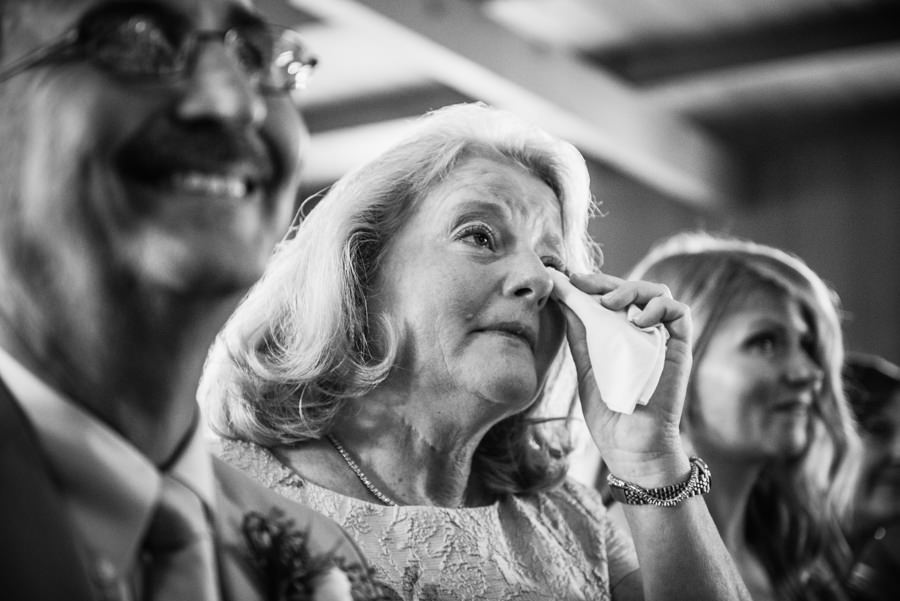 black and white candid portrait of mother of bride crying during ceremony