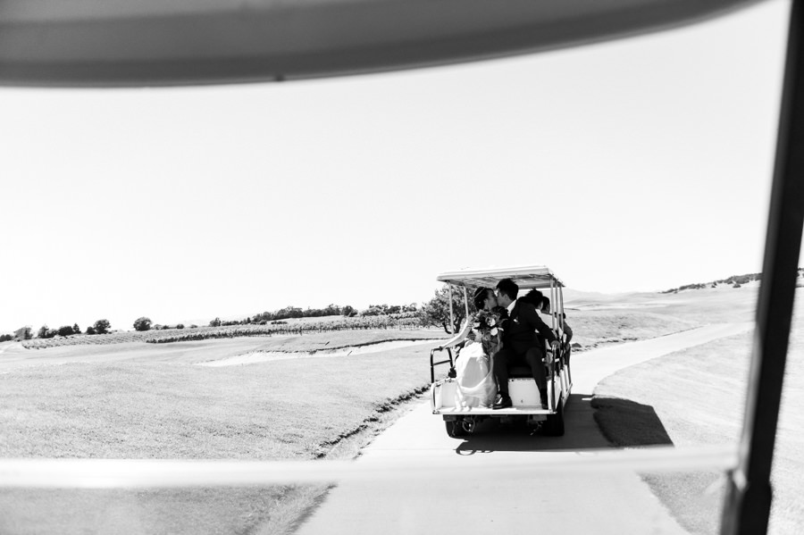 black and white candid portrait of couple kissing on golf cart during wedding