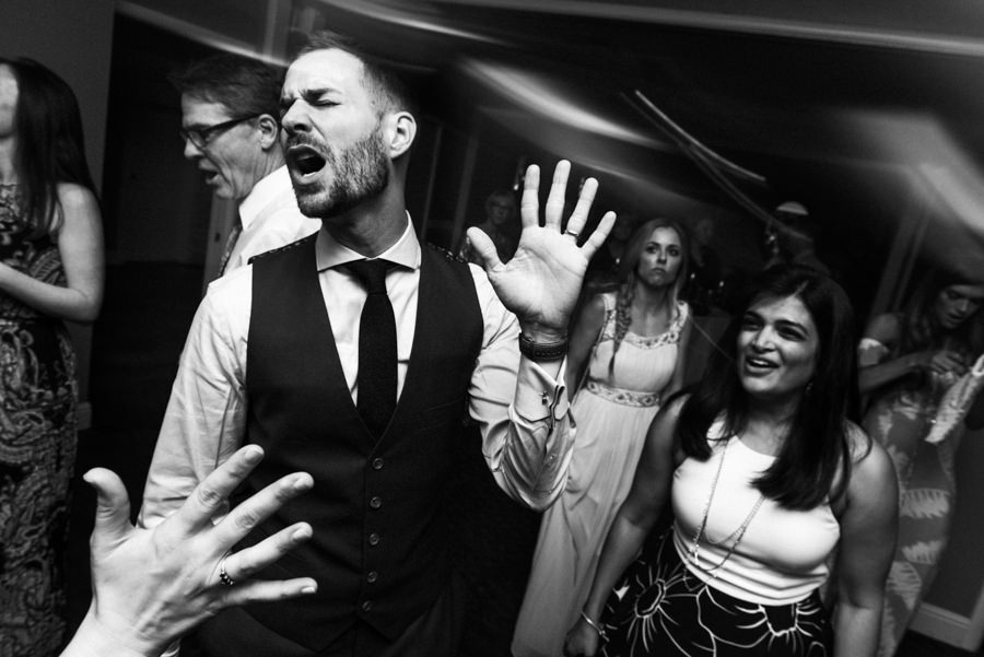 black and white candid portrait of groom dancing with eyes closed