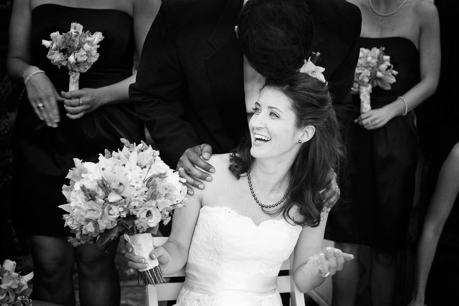 black and white candid portrait of groom kissing bride on top of head