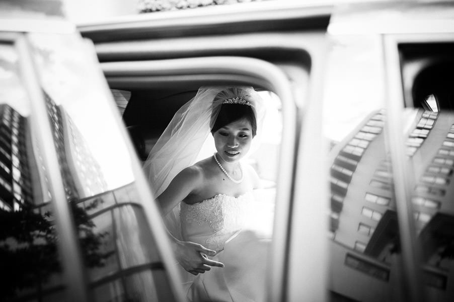 Black and white candid portrait of bride getting out of limousine with reflection of city in San Francisco